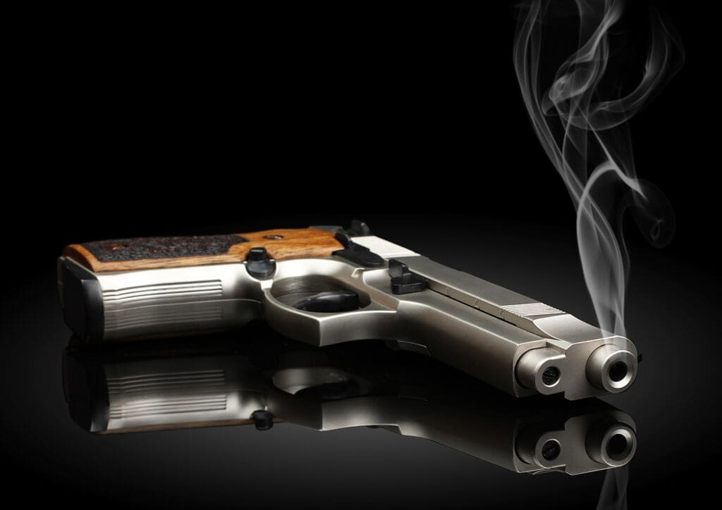 Handgun on black background with smoke.